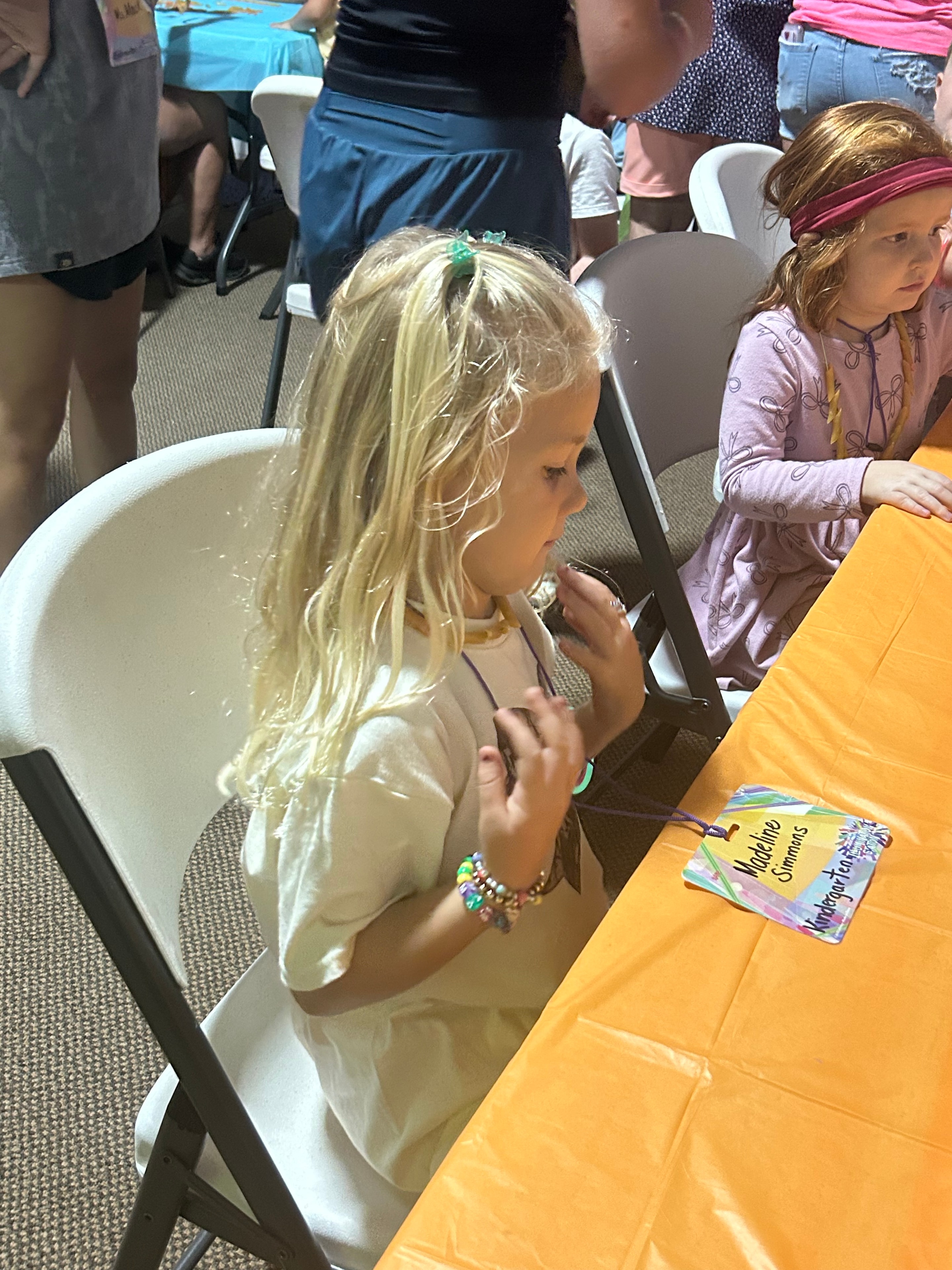 Young girl making a craft necklace at VBS 2026