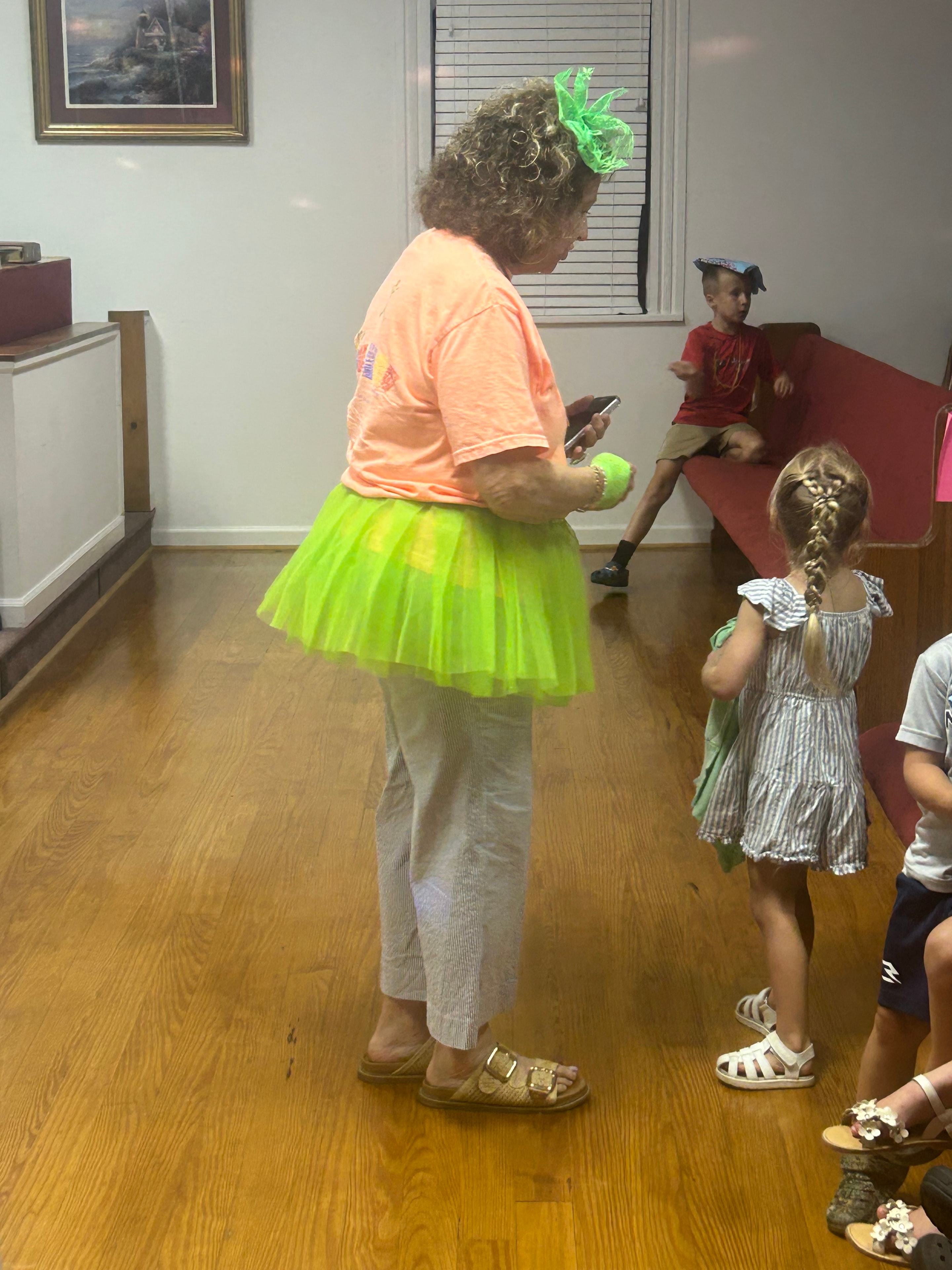 VBS volunteer in neon green tutu leading children in an activity