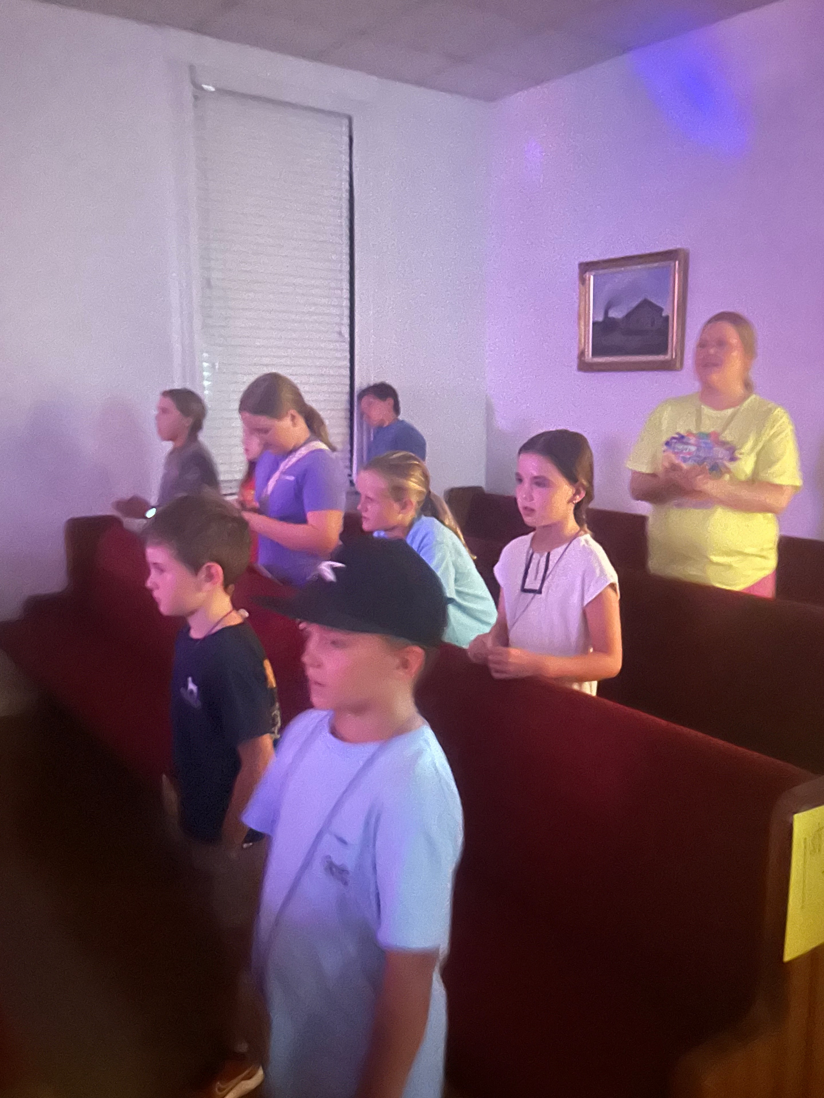 Older children and teens gathered in the sanctuary with purple lighting at VBS 2026
