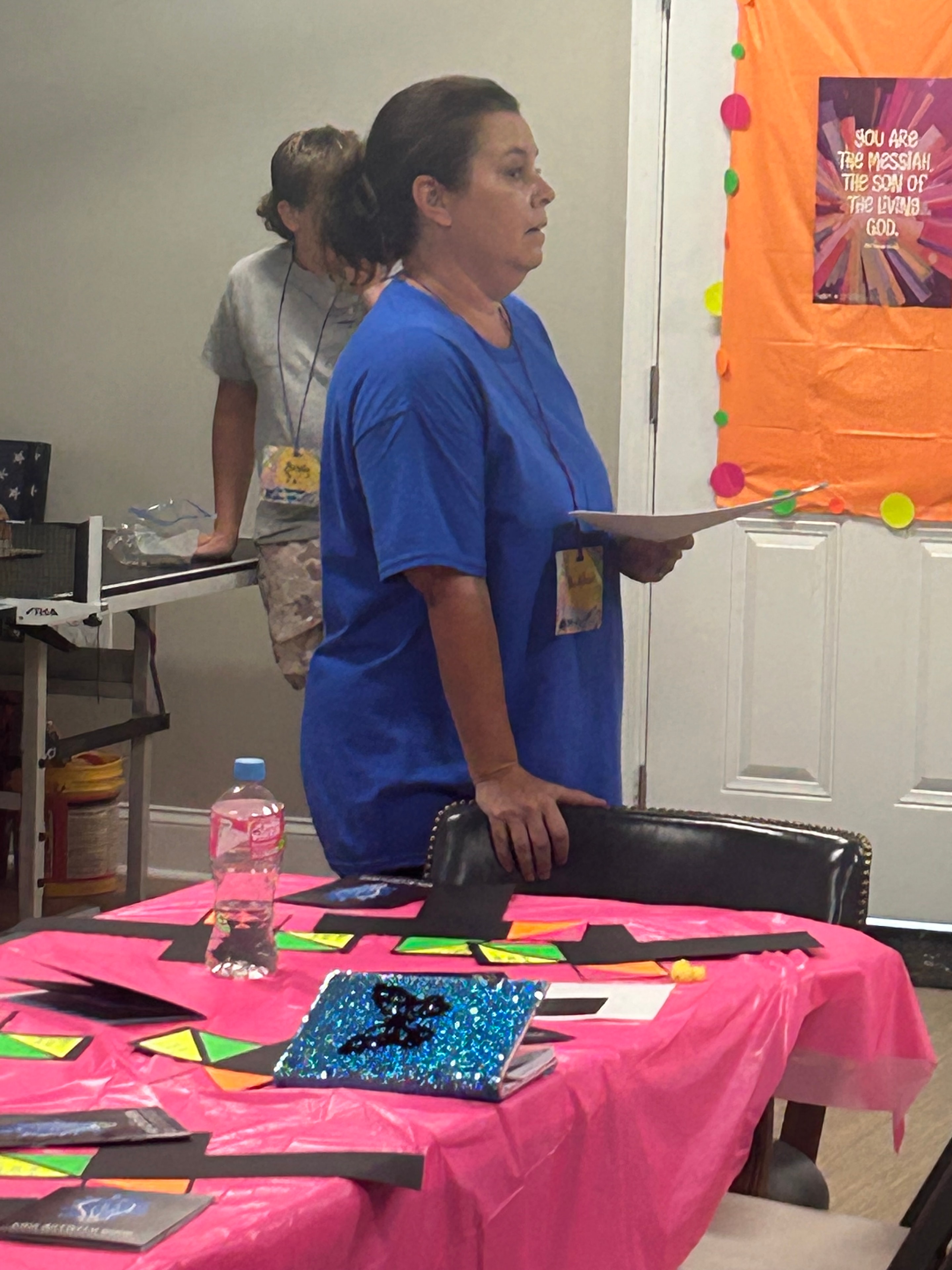 VBS volunteer at a colorful craft station with neon decorations