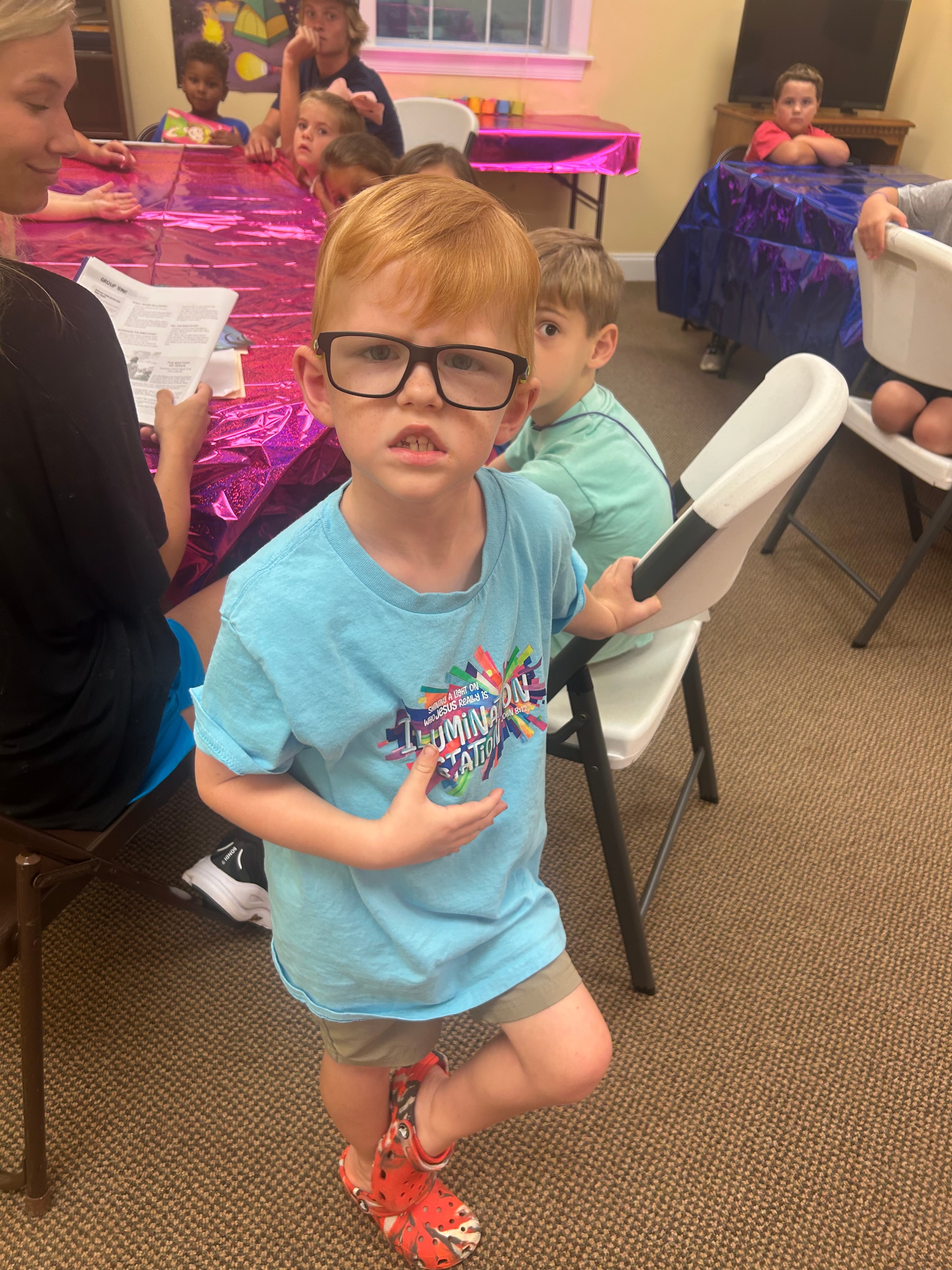 Young boy in VBS Illumination shirt posing in a classroom