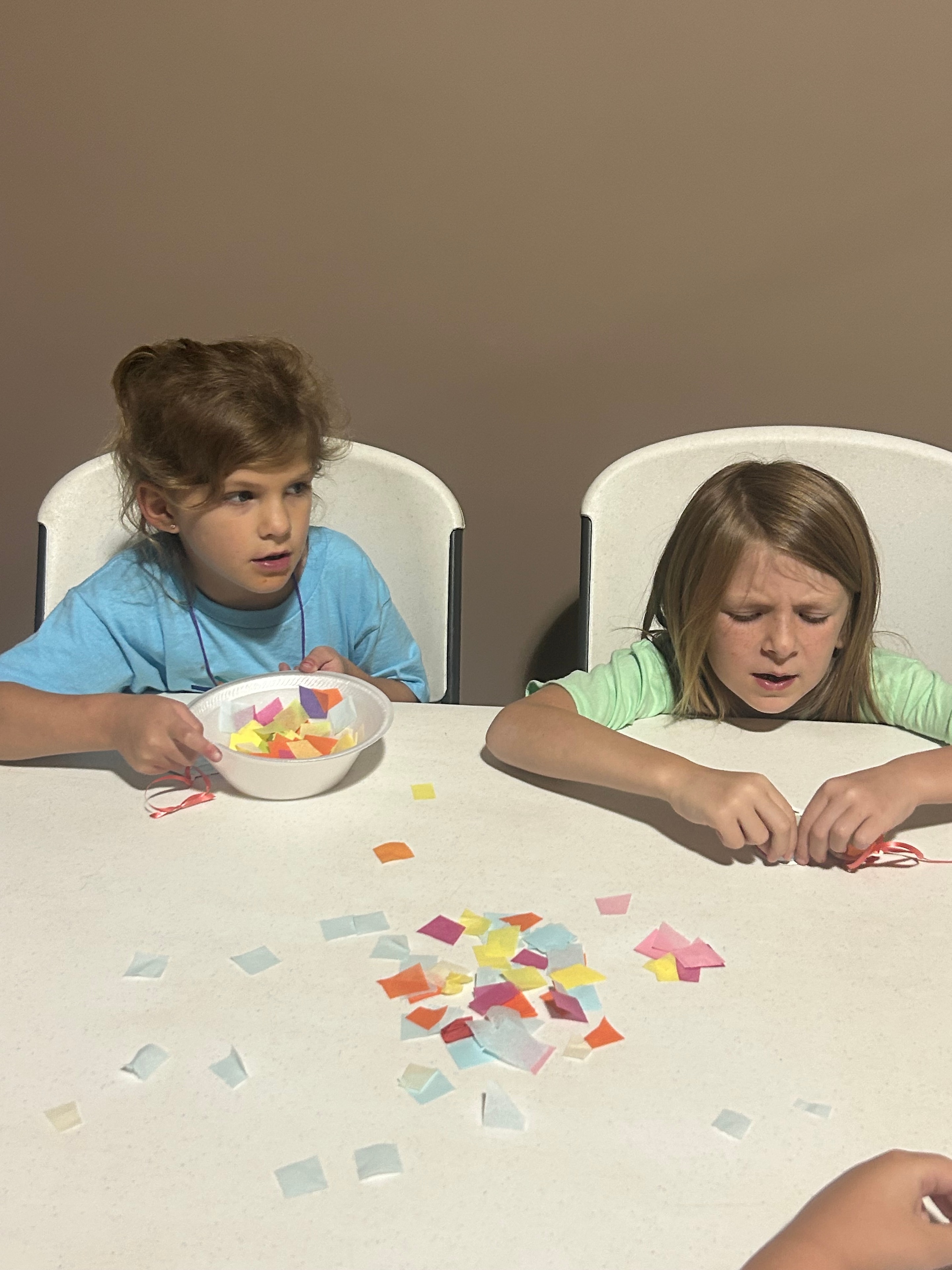 Two children working on a colorful paper craft project at VBS 2026