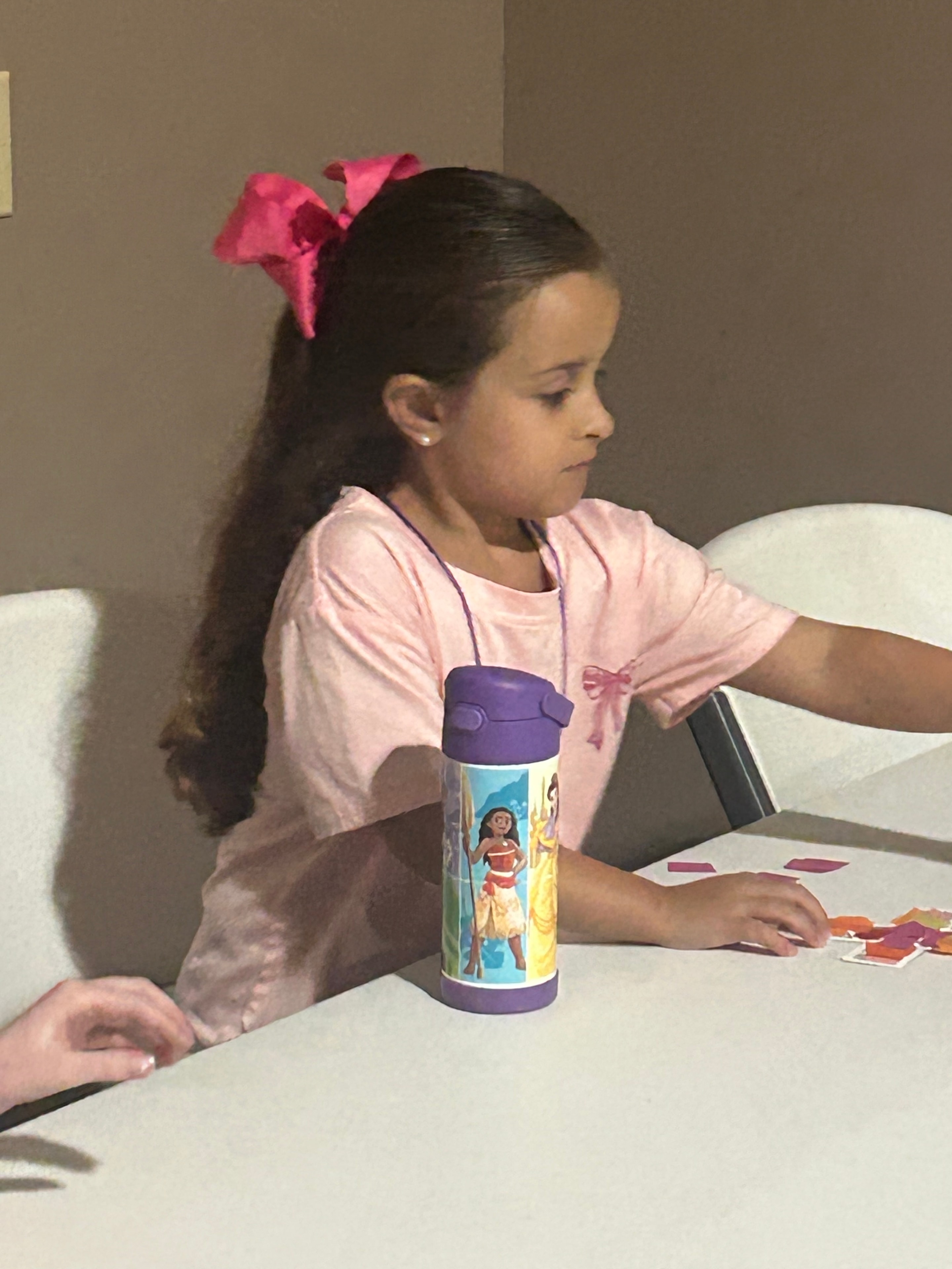 Girl in pink with Moana water bottle working on a craft at VBS 2026