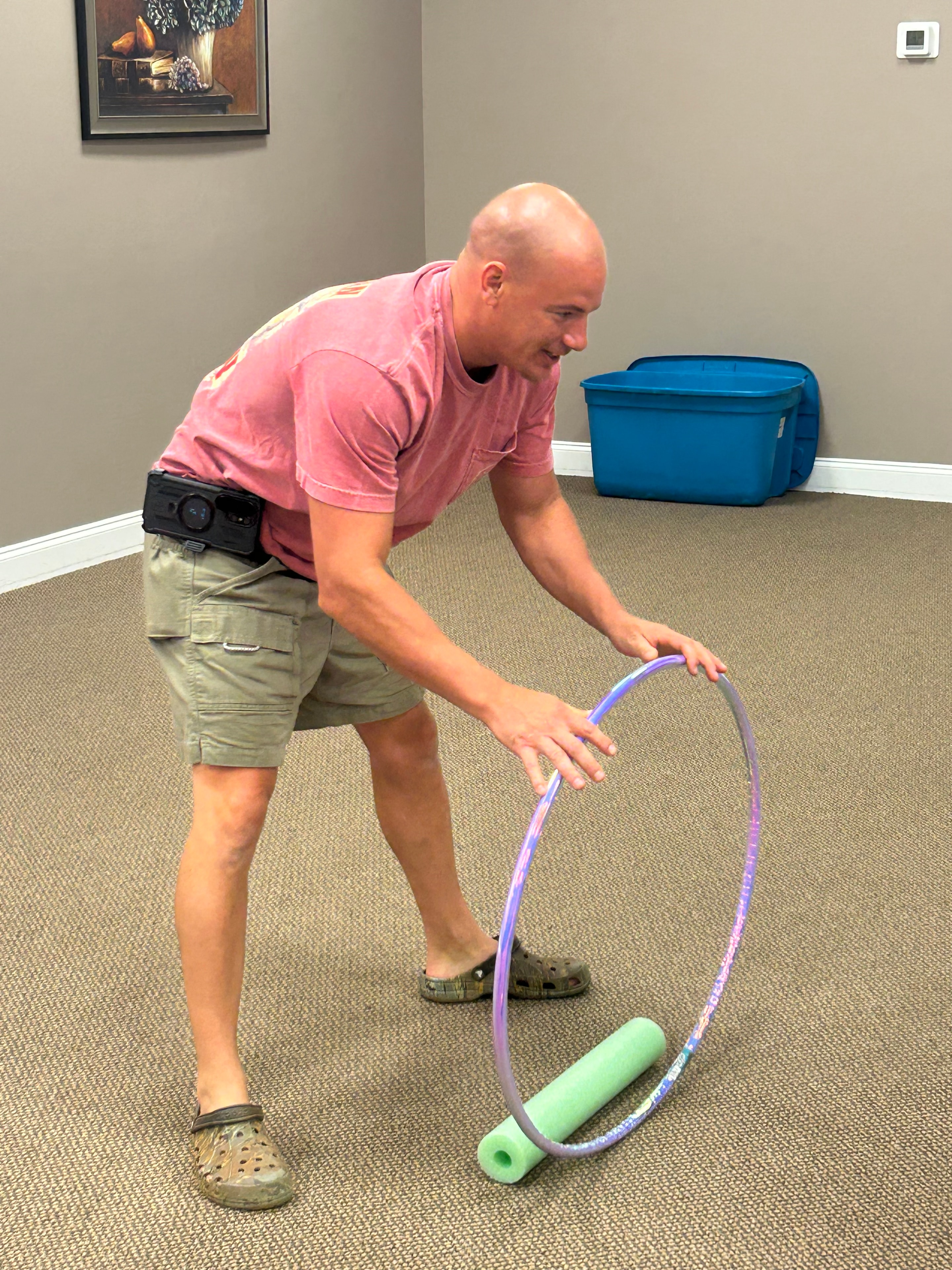 Volunteer on the floor spinning a hula hoop with a pool noodle at VBS 2026